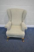 A WINGBACK ARMCHAIR, with patterned upholstery, raised on front cabriole legs, width 78cm x depth