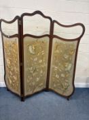 AN EDWARDIAN MAHOGANY THREE PANEL FOLDING SCREEN, with shaped bevelled glass, over tapestry inserts,