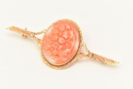 A CARVED CORAL BROOCH, an oval form carved floral detail, collet set with a surround of yellow