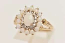 A 9CT GOLD GEM SET RING, designed as an oval opal prong set with a surround of round brilliant cut