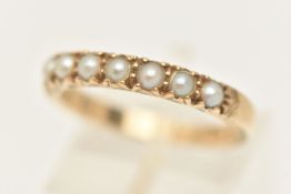 A YELLOW METAL GEM SET RING, designed as seven seed pearls prong set in a band with scrolling detail