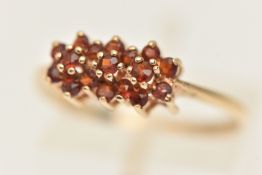 A 9CT GOLD GEM SET CLUSTER RING, designed as three rows of circular cut garnets, prong set in yellow