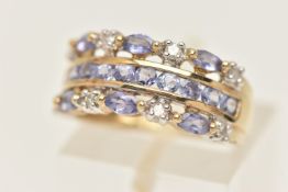 A 9CT GOLD GEM SET RING, designed as circular cut tanzanite's channel set in yellow gold with