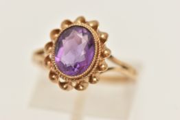 A 9CT GEM SET RING, designed and an oval cut amethyst, collet set in yellow gold, scalloped