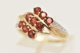 A 9CT GOLD GEM SET RING, designed as a nine stone circular cut garnet cluster with a twist mount