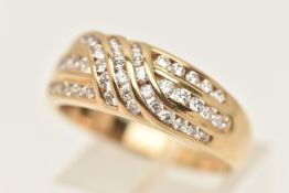 A 9CT GOLD GEM SET RING, designed as a yellow gold cross over band channel set with three rows of
