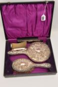 A CASED SILVER TRAVEL VANITY SET, comprising of a hair brush, mirror and comb with embossed floral