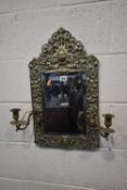 IN THE MANNER OF WILLIAM TONKS, A SMALL CAST BRASS GIRANDOLE WALL MIRROR, with ornate scrolled
