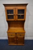 A MODERN PINE DRESSER, with double glass doors, atop a base with two drawers over double cupboard