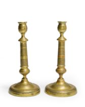 A pair of French brass candlesticks, first half 19th century, the urn sockets above tapering stem...