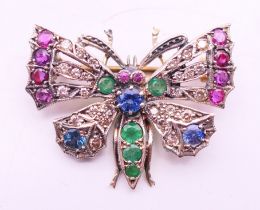 An unmarked gold multi gem set butterfly brooch. 3.5 cm x 2.75 cm.