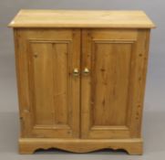 A pine two-door cupboard. 90 cm high x 83 cm wide x 40 cm deep.