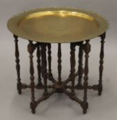 An Eastern brass-topped folding table. 68 cm diameter.