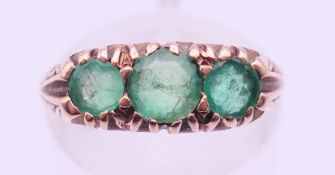 A 9 ct gold three stone emerald ring. Ring size M.