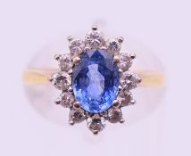 An 18 ct gold, diamond and blue stone flower head ring. Ring size M.