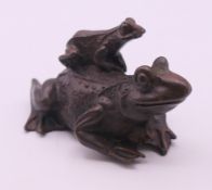 A bronze frog with a froglet on its back. 4.5 cm high.