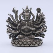 A white metal multi-armed seated deity. 4.5 cm high.