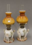 A pair of 19th century cherub-mounted porcelain oil lamps. 43.5 cm high.
