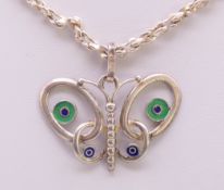 A silver and enamel butterfly pendant on a silver chain.