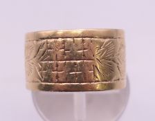 A 9 ct gold florally-engraved wedding band. 1 cm high, ring size N/O. 4.4 grammes.