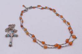 A silver cross on a silver chain and an agate and silver necklace.