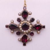 An unmarked garnet and seed pearl brooch. 3.5 cm x 3.5 cm.