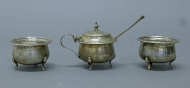 A three-piece silver cruet set and spoon. The mustard 6 cm high. 122 grammes.