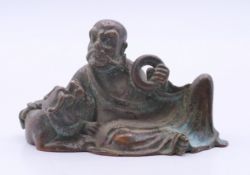 A bronze of a reclining deity with dog-of-fo. 6 cm long, 4 cm high.