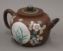 A 19th/20th century Chinese Yixing teapot and strainer painted with flowers in bright enamels.