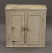 A small painted pine cupboard. 62.5 cm wide x 63 cm high.