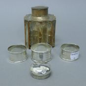 Three silver napkin rings, a silver lid and a silver-plated tea caddy. The latter 9.5 cm high. 69.