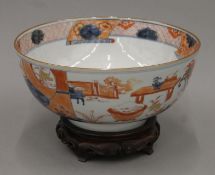 An 18th century Chinese porcelain underglaze blue and iron red decorated punch bowl on a carved