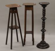 Two early 20th century oak torcheres and a barley twist example. The latter 97 cm high.