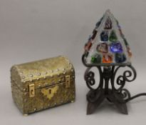A wrought iron Art and Crafts-style table lamp and a brass casket. The former 32 cm high.