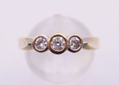 An unmarked gold three-stone diamond ring. Ring size P. 3.7 grammes total weight.