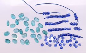 A quantity of loose facet-cut emeralds and small sapphire beads.