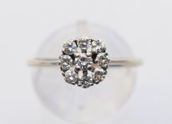 An 18 ct white gold and diamond flowerhead ring. Ring size P/Q. 2 grammes total weight.