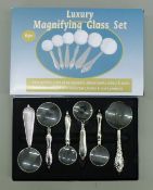A boxed six-piece magnifying glass set. The box 21.5 cm wide.
