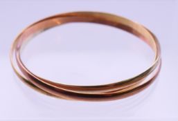 A 9 ct gold tri-colour bracelet. 6 cm inner diameter. 23.8 grammes.