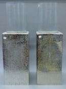 A pair of glass storm lamps with chrome stands. Each 79 cm high.