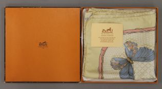 A boxed Hermes silk scarf decorated with flowers and butterflies. 85 x 85 cm.