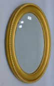 An early 20th century bevelled gilt-framed oval wall glass. 64 cm high.