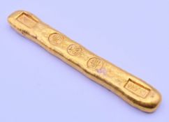 A gold coloured bar scroll weight. 12 cm long.