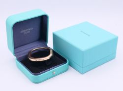 A boxed Tiffany & Co 18 ct gold and diamond (0.32 carat) lock bangle. 0.5 cm high, 5.