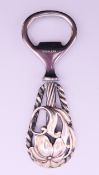 A white metal handled bottle opener. 11 cm high.