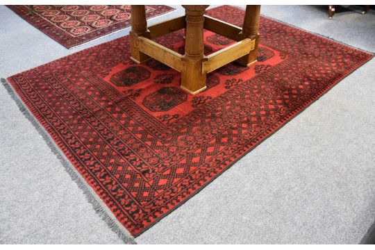 Afghan Turkmen Rug, the light claret field with eight elephant foot güls enclosed by multiple - Image 1 of 2