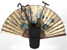 A metal bound stick pot containing walking sticks, parasol, a large oriental fan, etc.