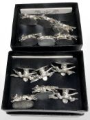 Two sets of six white metal menu card holders in the form of running foxes.