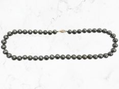 A cultured grey pearl single-strand necklace with gold clasp stamped 14K,