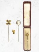 A gold horseshoe stick pin, a further gold acorn ornament,